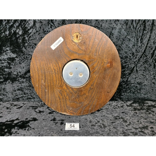 54 - Aneroid barometer with a silvered dial, a brass bezel, and housed in a carved wooden case. Approx Di... 