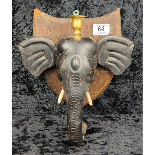 64 - Anglo-Indian carved ebony elephant head wall plaque, on a mahogany backboard and brass candle holder... 