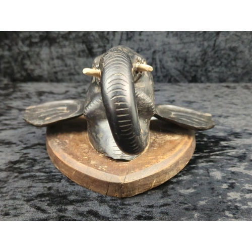 64 - Anglo-Indian carved ebony elephant head wall plaque, on a mahogany backboard and brass candle holder... 