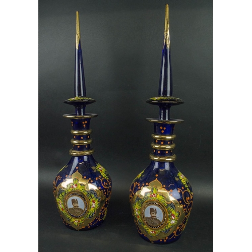 403 - NASSER AL DINE SHAH QAGAR DECANTERS, a pair, blue ground with portrait in cartouche handpainted foli... 