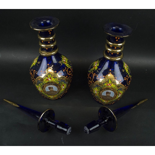 403 - NASSER AL DINE SHAH QAGAR DECANTERS, a pair, blue ground with portrait in cartouche handpainted foli... 