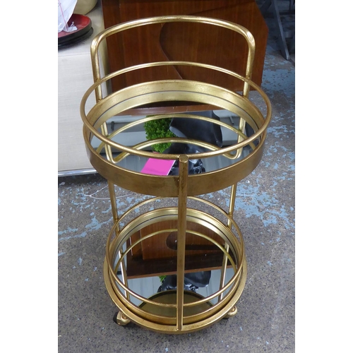 630 - DRINKS TROLLEY, 1960's French style, gilt metal, two mirrored tiers, 76.5cm H x 45cm Diam approx.