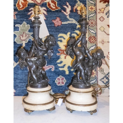 395 - TABLE LAMPS, a pair, 57cm H, bronzed metal, cherubs holding aloft a torchiere, on rounded marble and... 