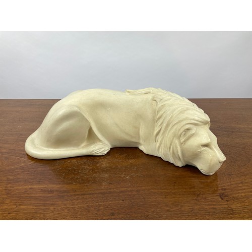 369 - SLEEPING LION, carved sandstone. 45cm L