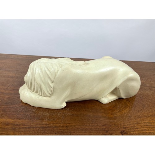 369 - SLEEPING LION, carved sandstone. 45cm L