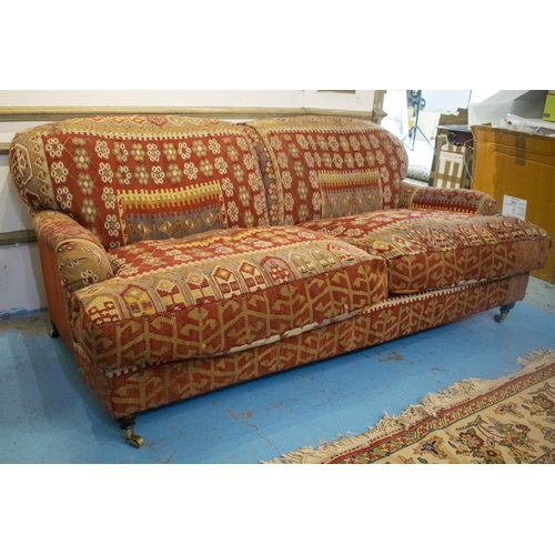 256 - KILIM SOFA, 186cm x 94cm, three seater with turned feet and brass castors.