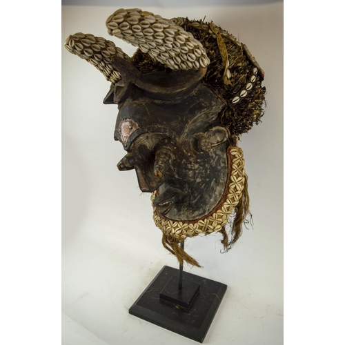 116 - KUBA MASK, Congolese, ornately carved wood, adorned with Cowrie shells and grass fiber 90cm H