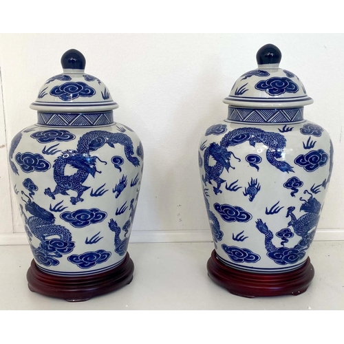 480 - CHINESE DRAGON URNS AND COVERS, 38cm x 22cm, blue and white under glaze decoration, with stands. (2)