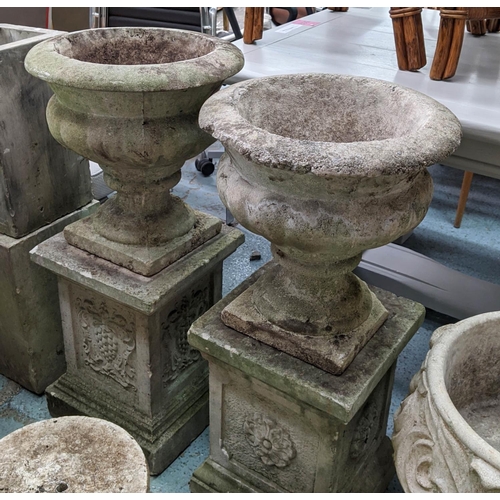 362 - ARCHITECTURAL GARDEN URNS, on stands, a set of two, composite stone, grape detail on one pedestal ro... 