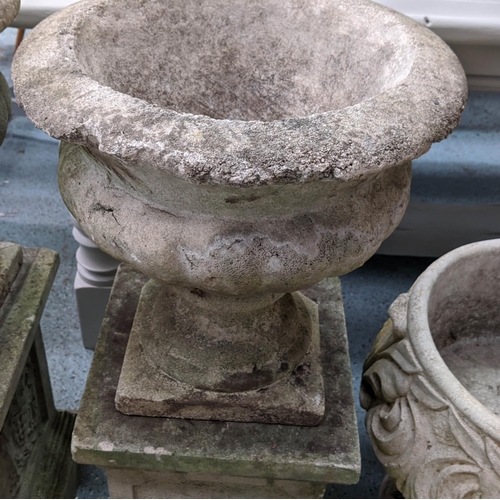 362 - ARCHITECTURAL GARDEN URNS, on stands, a set of two, composite stone, grape detail on one pedestal ro... 