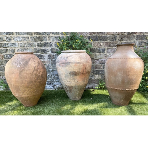 592 - OLIVE JARS, three weathered terracotta each of lapening cylindrical form with some sqrattito decorat... 