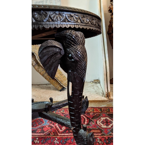 265 - OCCASIONAL TABLE, Indian carved ebonised wood with oval top and elephant detail, 76cm W x 52cm D x 6... 