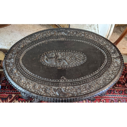 265 - OCCASIONAL TABLE, Indian carved ebonised wood with oval top and elephant detail, 76cm W x 52cm D x 6... 