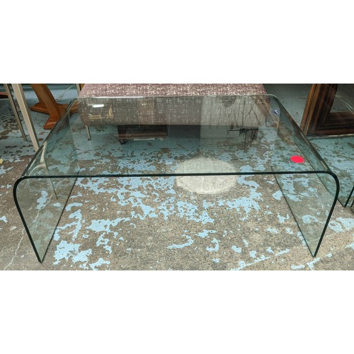 425 - CURVED GLASS COFFEE TABLE, 60cm D x 40cm H x 100cm W.