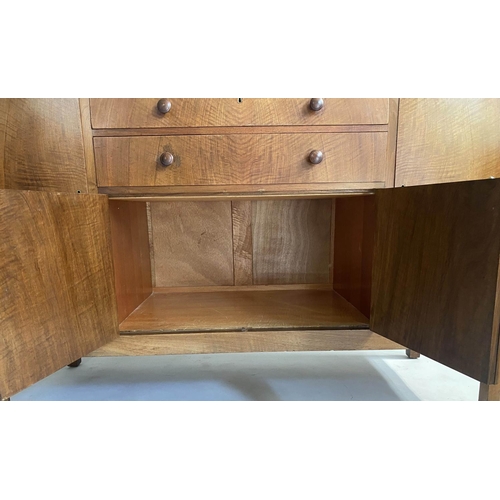 504 - HEALS SIDEBOARD, 1950s figured walnut, with drawers and cupboards flanked by further cupboards, labe... 