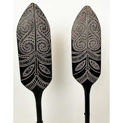 15 - MAORI STYLE PADDLES, a pair, on ebonised stands, 143cm H. (2)