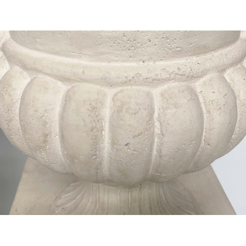 171 - URNS ON STANDS, a pair, campana form stone effect on plinths, 46cm W x 135cm H.