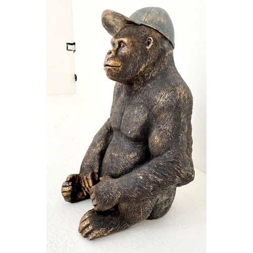 373 - GORILLA WEARING CAP, 58cm high, 40cm wide, 34cm deep, faux bronze finished resin.