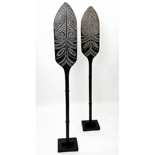 19 - MAORI STYLE PADDLES, a pair, on ebonised stands, 143cm H. (2)