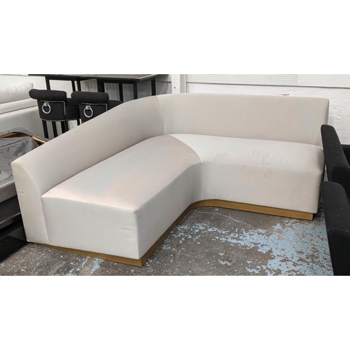 525 - CORNER SOFA, neutral upholstered, gilt plinth base, 84cm H x 190cm W x 190cm L x 90cm D.