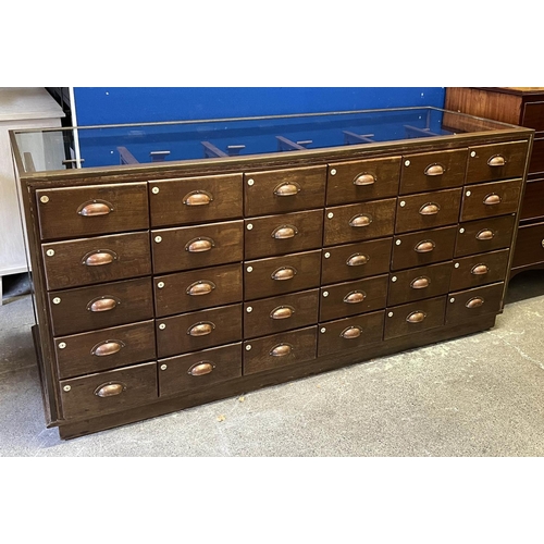 547 - HABERDASHERY COUNTER, oak and bronze framed with glass sides and back with an arrangement of 30 draw... 