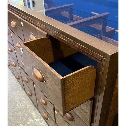 547 - HABERDASHERY COUNTER, oak and bronze framed with glass sides and back with an arrangement of 30 draw... 