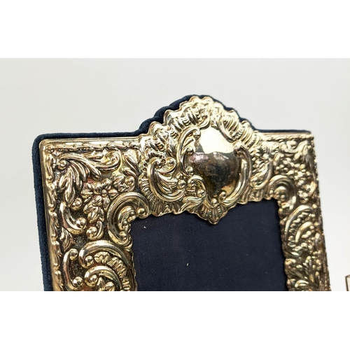 15 - A COLLECTION OF SILVERWARE, comprising Rococo embossed photo frame, three smaller photo frames, a ma... 