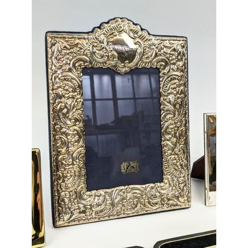 15 - A COLLECTION OF SILVERWARE, comprising Rococo embossed photo frame, three smaller photo frames, a ma... 