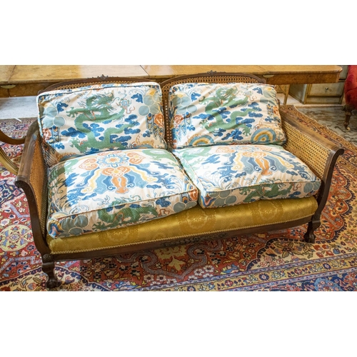 289 - BERGERE SOFA, 76cm H x 147cm W, early 20th century with double caned arms and loose cushions in drag... 