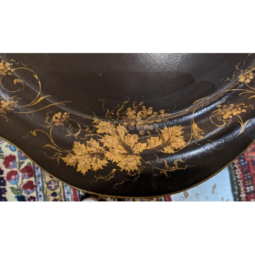 111 - VICTORIAN TRAY ON STAND, black papier mâché,  scalloped oval gilt vine leaf decoration, folding, on ... 