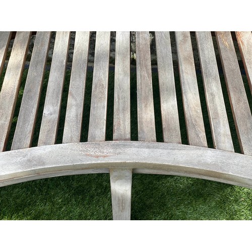 299 - BANANA GARDEN BENCH, weathered teak and slatted of arched form, 160cm W.