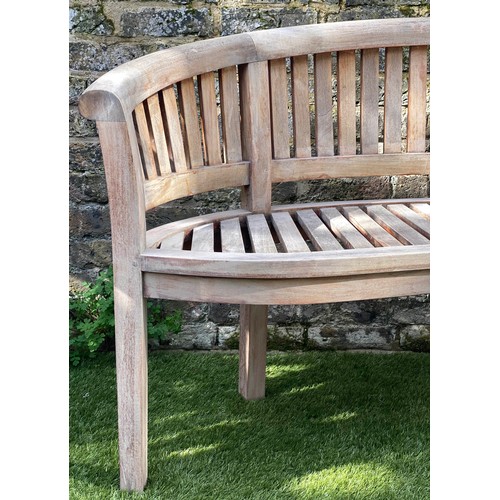 299 - BANANA GARDEN BENCH, weathered teak and slatted of arched form, 160cm W.