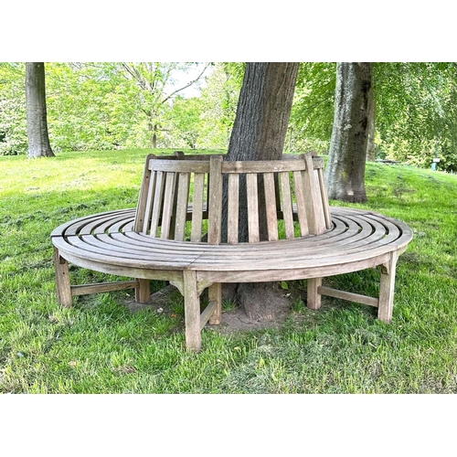 181 - GARDEN TREE BENCH, weathered teak in two sections, with slatted upstand and concentric slatted seat,... 