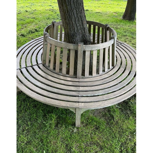 181 - GARDEN TREE BENCH, weathered teak in two sections, with slatted upstand and concentric slatted seat,... 