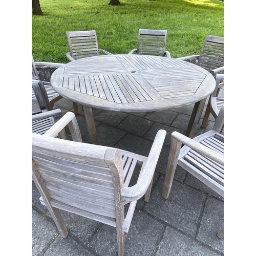 355 - GARDEN TABLE AND ARMCHAIRS, weathered, eight stacking armchairs included 64cm W, table 130cm W. (9)