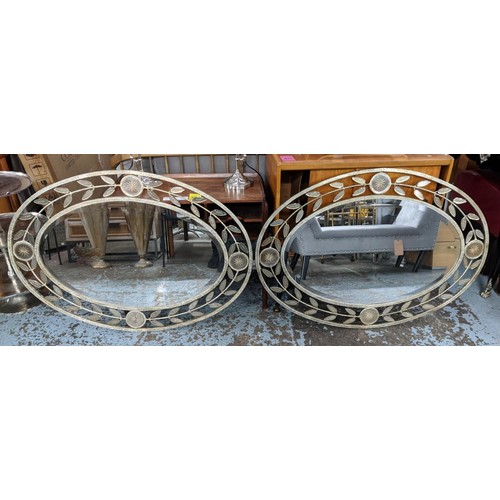 427 - OVAL MIRRORS, a pair, each 75cm W x 107cm H, with distressed metal frames and leaf motif border. (2)