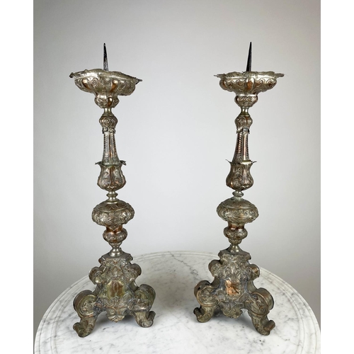 19 - ECCLESIASTICAL PRICKET CANDLESTICS, a pair, ornately embossed silvered copper, 75cm H. (2)