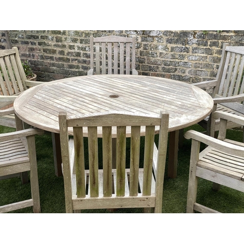 489 - CIRCULAR GARDEN TABLE AND CHAIRS, silvery weathered teak, including a set of six armchairs by Lister... 