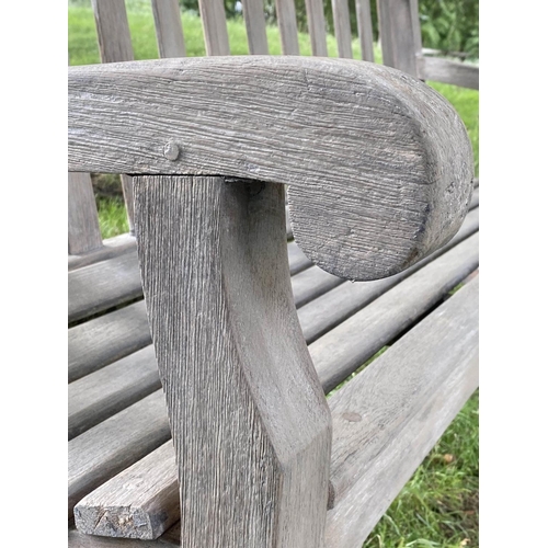 493 - LISTER GARDEN BENCH, well weathered teak of Country House proportions, slatted with scroll arms, R A... 