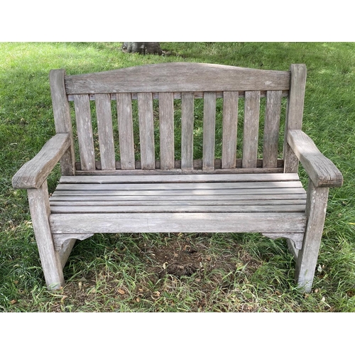 495 - GARDEN BENCH, weathered teak of slatted and pegged construction with flat top arms and arched back, ... 