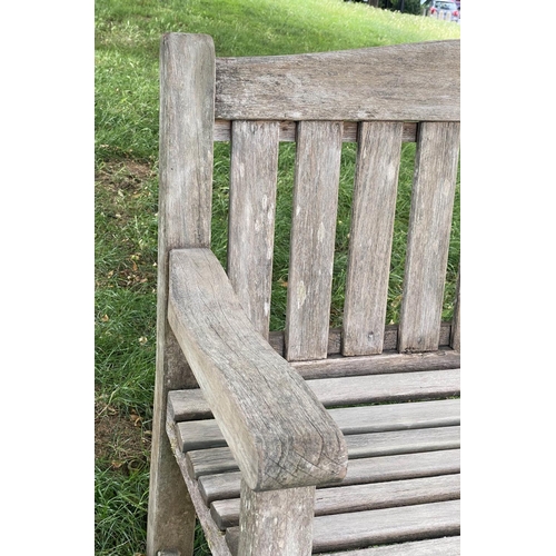 495 - GARDEN BENCH, weathered teak of slatted and pegged construction with flat top arms and arched back, ... 