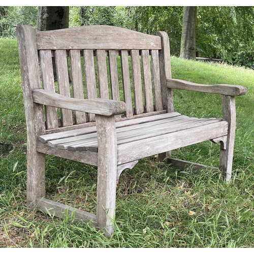 495 - GARDEN BENCH, weathered teak of slatted and pegged construction with flat top arms and arched back, ... 