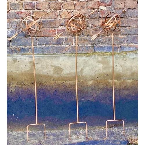 383 - ARMILLARY SPHERE GARDEN STAKES, a set of three, 115cm H x 39cm W x 17cm D, coppered metal finish. (3... 