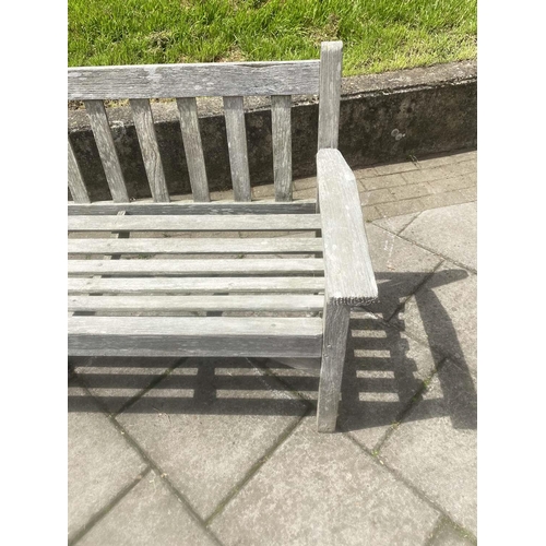 411 - LISTER GARDEN BENCH, silvery weathered teak of slatted construction with flat top arms by R A Lister... 