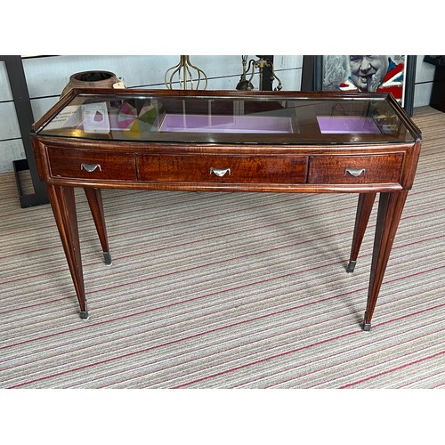 195 - BIJOUTERIE TABLE, 115cm W x 76cm H x 47cm D Art Deco manner with a glass top above three drawers on ... 