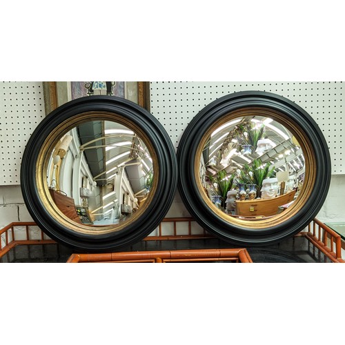 353 - CONVEX MIRRORS, a pair, 49cm diam ebonised  with a gilt inner slip. (2)