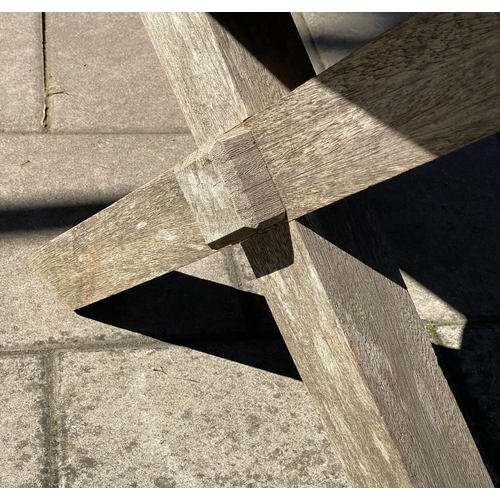 111 - GARDEN TABLE, weathered teak of substantial slatted construction with 'X' trestle and stretchered su... 