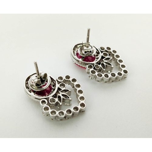 13 - A PAIR OF 18CT WHITE GOLD RUBY AND DIAMOND EARRINGS, each set with a single natural oval mixed cut r... 