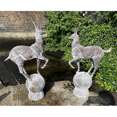 545 - SCULPTURAL STAGS, a pair, 100cm high, 60cm wide, cast metal, on globular bases. (2)