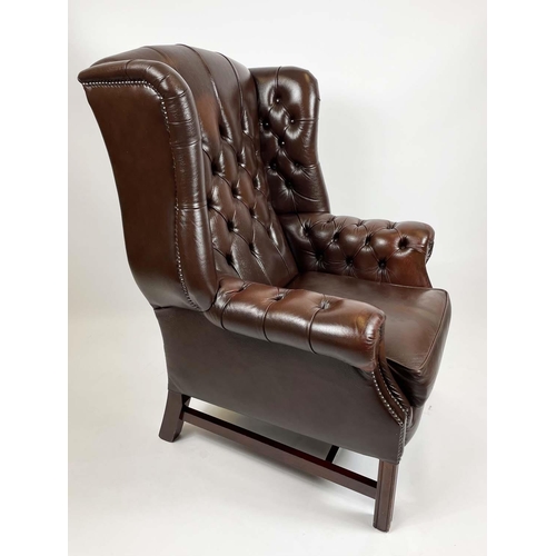 169 - WING ARMCHAIR, deep buttoned brown leather, with brass stud work and stretchered legs with buttoned ... 